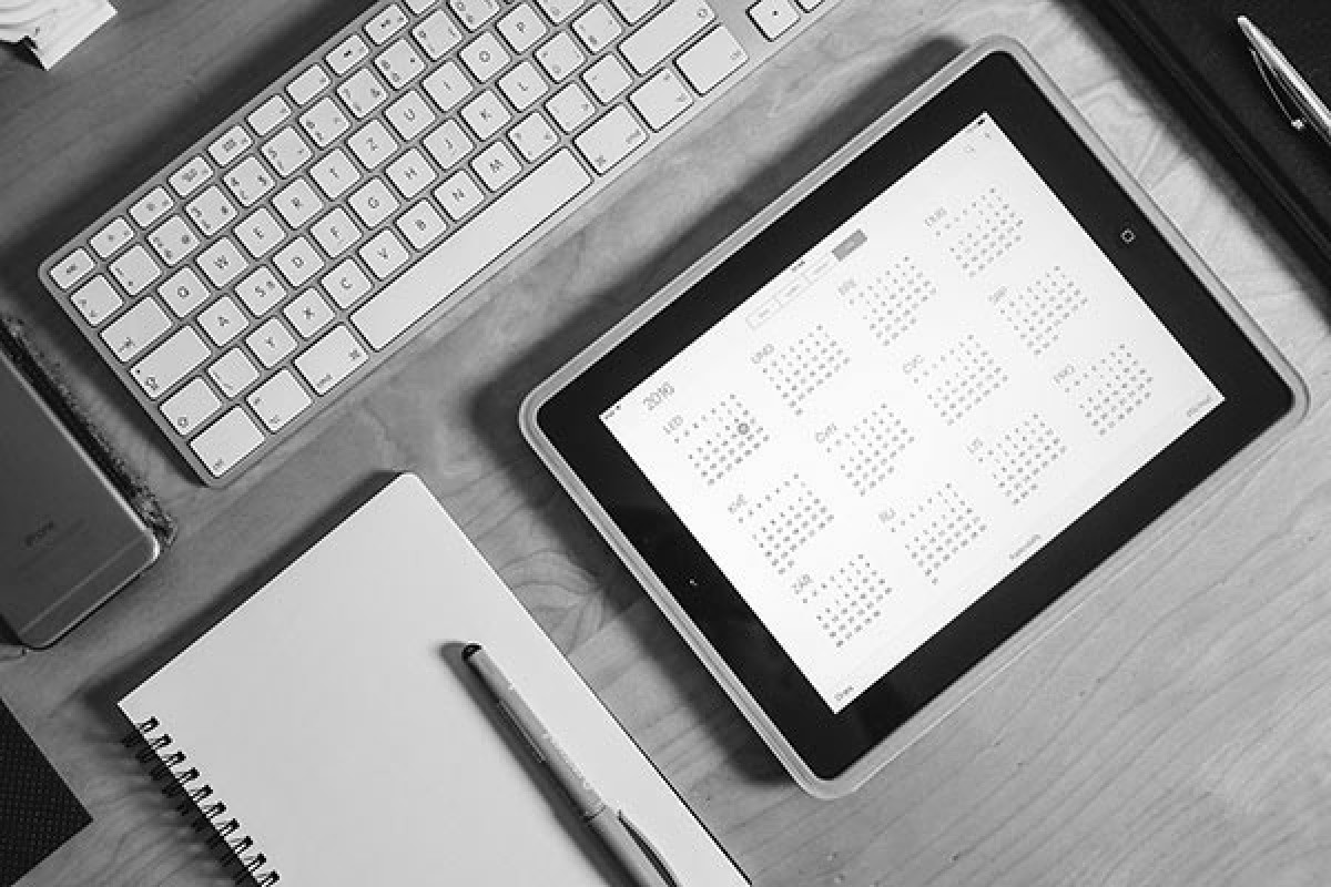 Desk with keyboard, notepad and ipad with calendar displayed