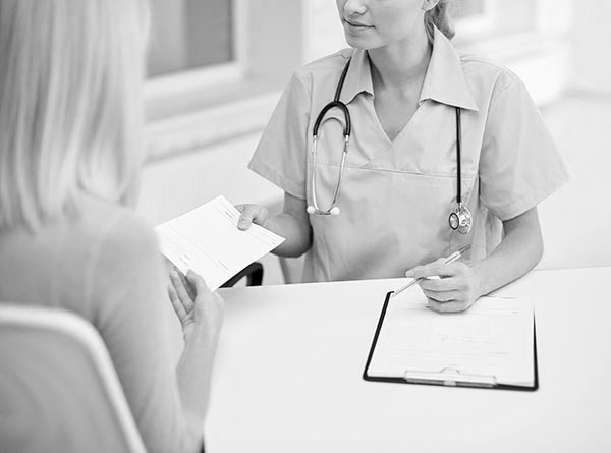 Femail doctor handing form to patient.